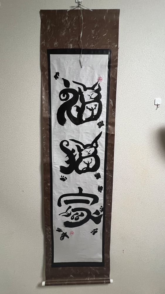 A calligraphy of the characters 福猫家 reimagined to look like sassy cats. There are paw prints of ink all over the scroll, as demonstrated through history, these paws will turn up just about everywhere.